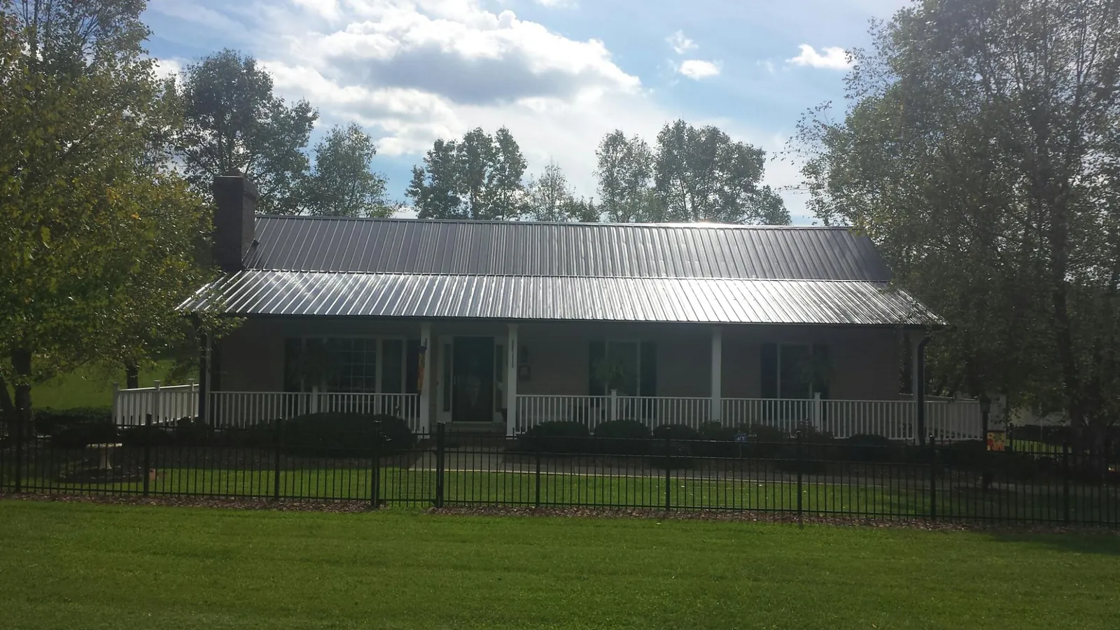 Gray metal roof on a brick ranch with a full width front porch — Gutter Guard Installation work by our crew in Valley