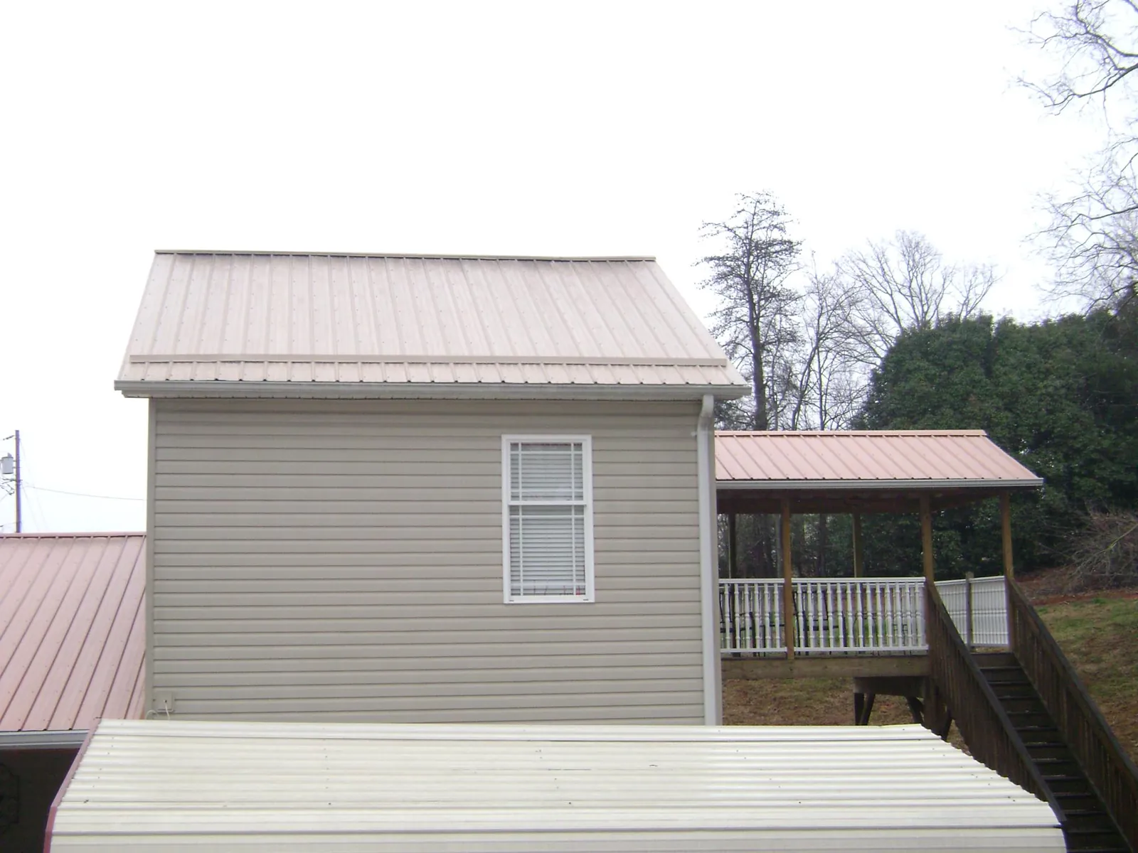 Tan metal roofs on a two story addition and attached porch, from a Roof Replacement job in Valley